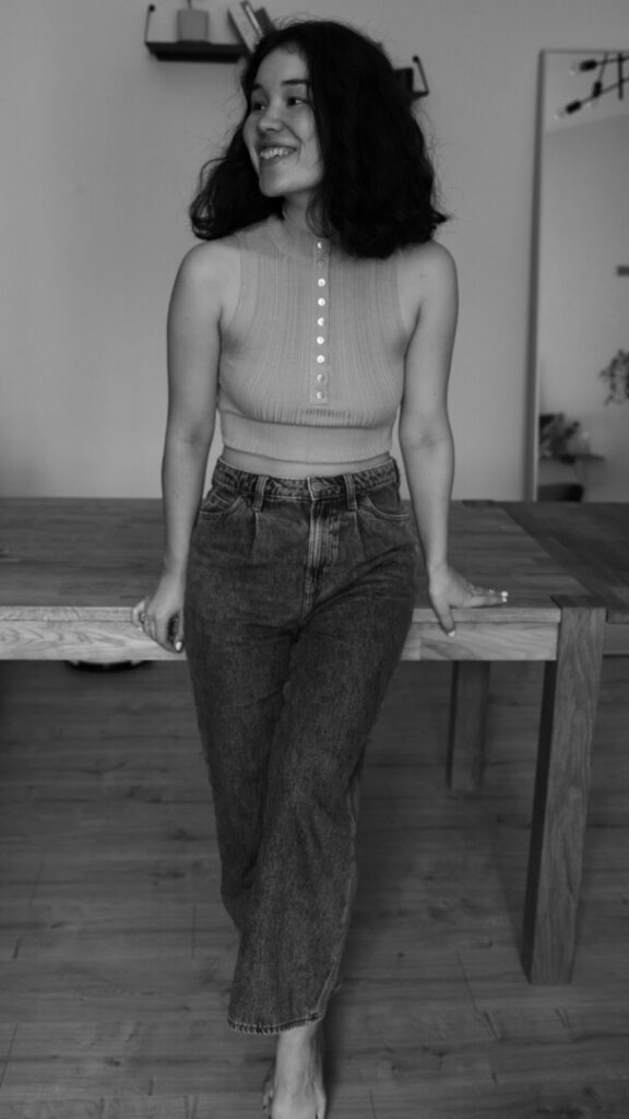 female creative entrepreneur in her office smiling while leaning on work table